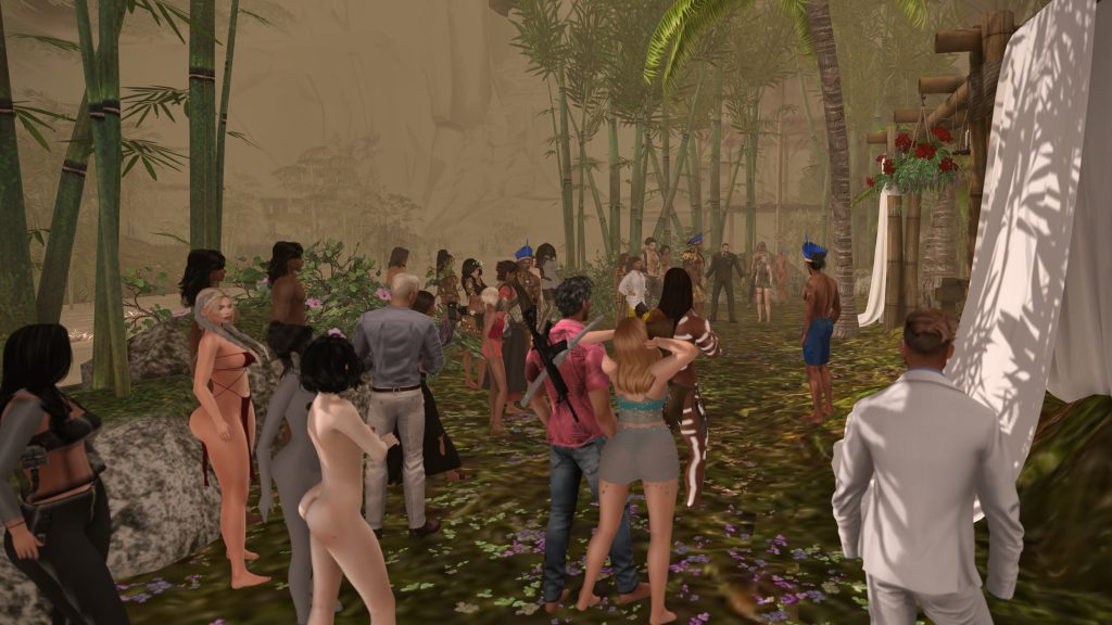 A diverse gathering of clothed and bare-footed men and women in a jungle setting, surrounded by lush bamboo and palm trees.