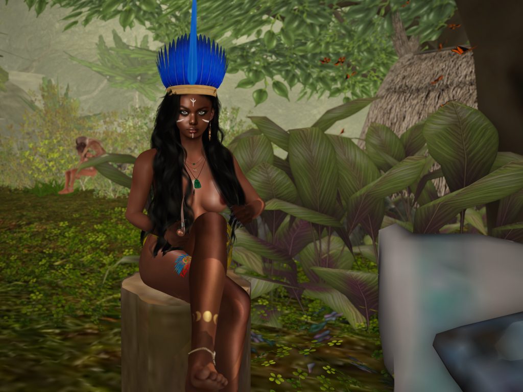 A native woman sits on a wooden stump in a green setting, wearing a blue feather headdress and jewelry. She is bare, with body paint on her leg.