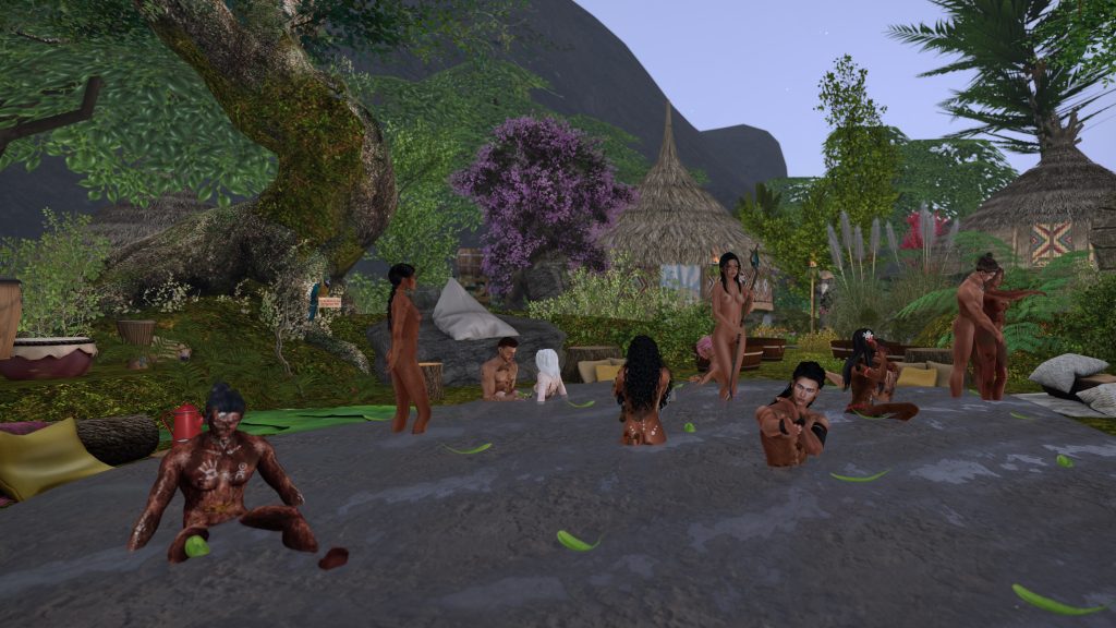 Villagers gather in a river, some unclothed, near a jungle camp with huts and lush vegetation