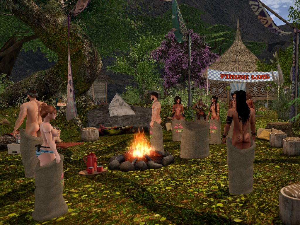 Topless native women race in sacks around a campfire in the jungle camp