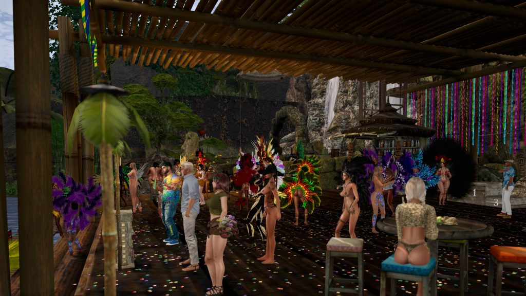 Dancers in feathered costumes dance under a bamboo canopy at the jungle camp by the waterfall