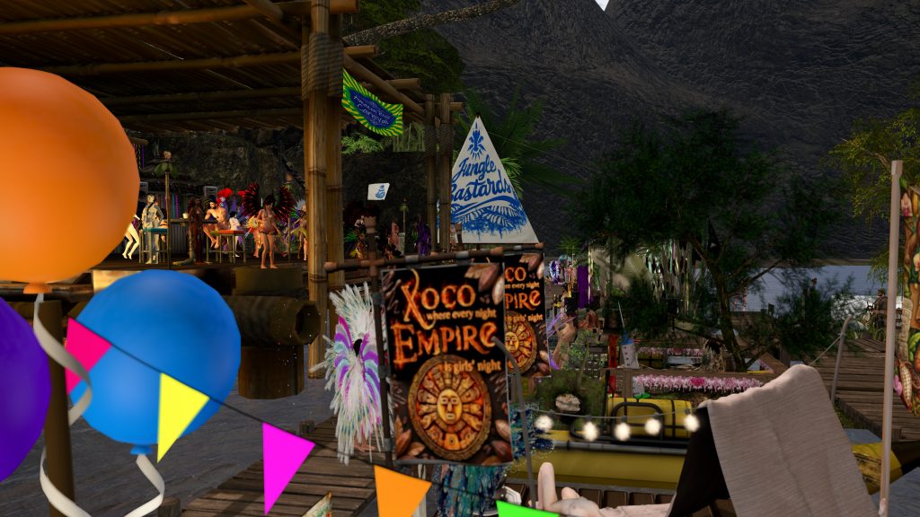 Dancers in feather headdresses perform on a bamboo stage at the jungle riverbank festival as villagers watch