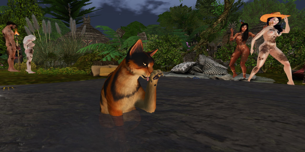 Large jungle cat laps its paw in shallow water as topless native women and a shirtless villager look on at camp