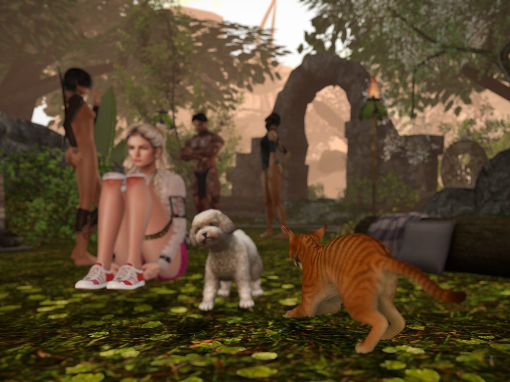 Villager in shorts sits beside a small dog while others gather at the jungle camp