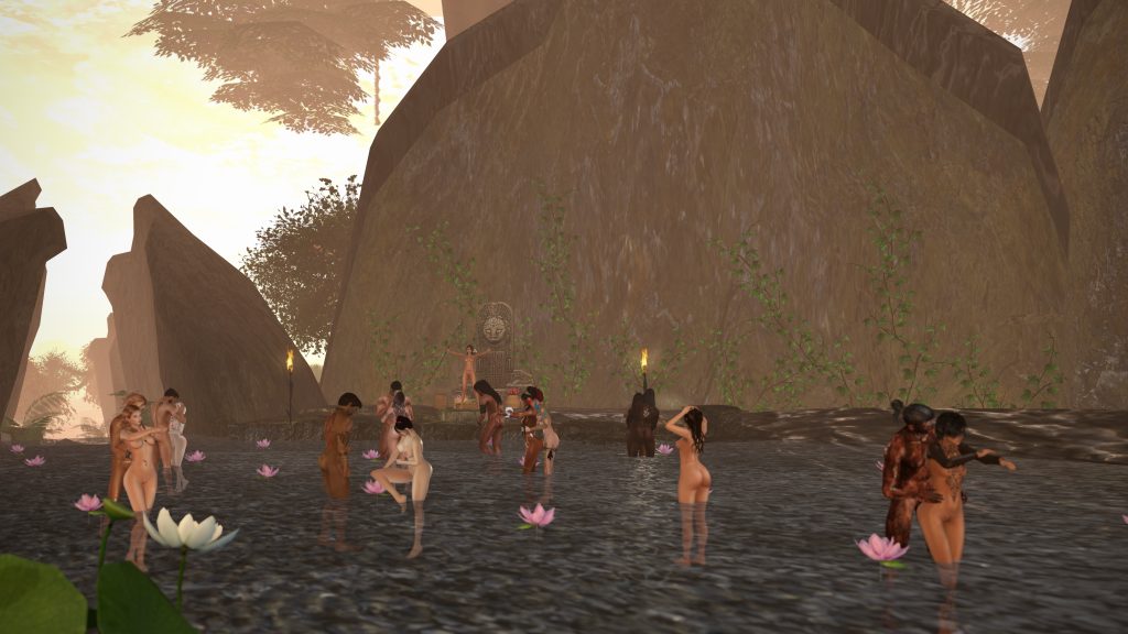Villagers unclothed bathe and dance in the shallow river by a carved stone shrine at dusk